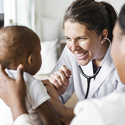 Doctor with stethoscope smiling at baby