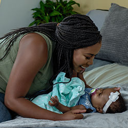 Mom smiling at baby on bed